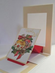 Handgjort julkort med texten “God Jul”, två klassiska julkulor med röd rosett och guldkanter, samt stafflivikning i rött och beige.